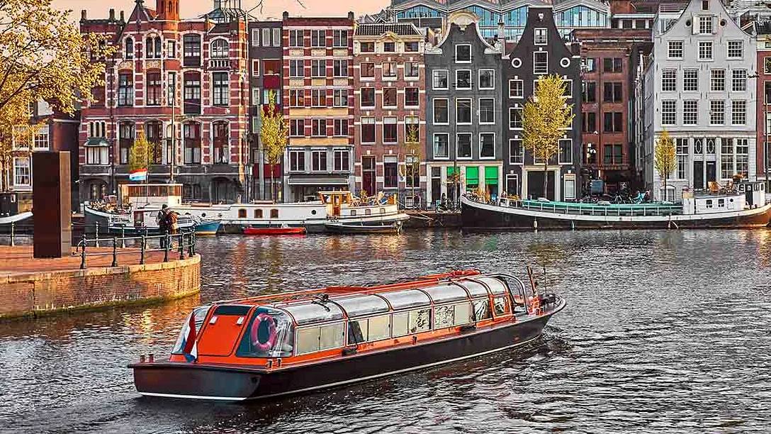 Amsterdam canal boat in front of canal houses